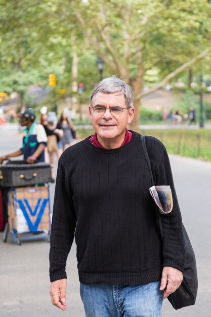 Hombre mayor retirado en el parque, caminando y relajándose, expresión sonriente