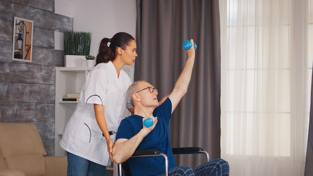 Hombre mayor en silla de ruedas haciendo recuperación profesional de lesiones. Discapacitado anciano discapacitado con trabajador social en terapia de apoyo a la recuperación fisioterapia sistema sanitario hogar de ancianos de enfermería