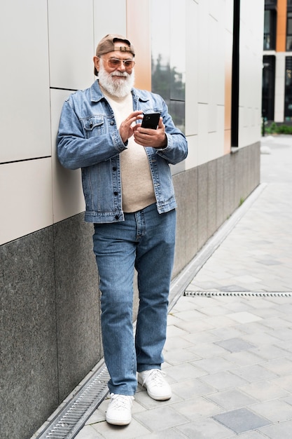 Foto hombre mayor con smartphone al aire libre en la ciudad