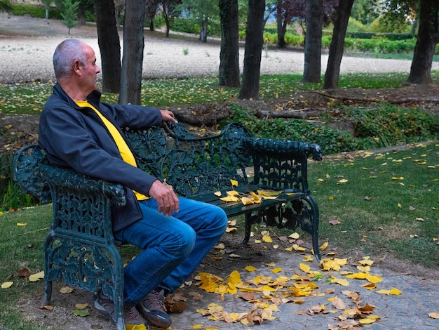 Un hombre mayor solo sentado en un banco del parque perdiendo a su pareja el concepto de soledad