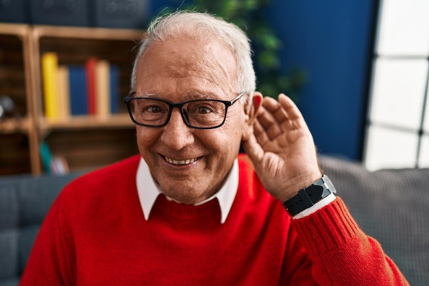 Hombre mayor sonriendo confiado usando audífonos para sordera en casa