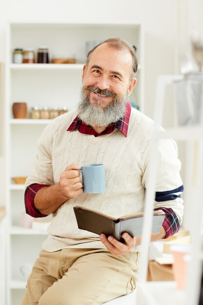 Hombre mayor sonriente que disfruta del café de la mañana