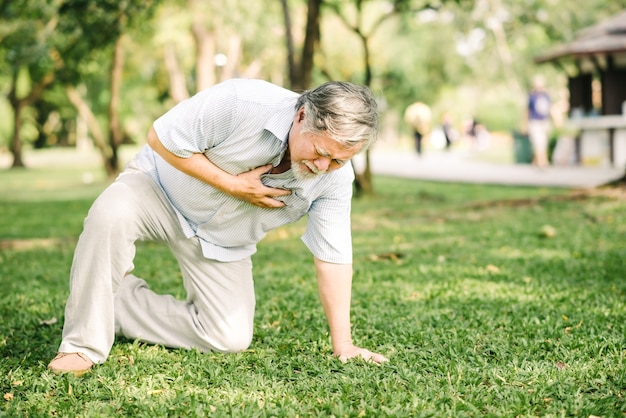 Hombre mayor sosteniendo su pecho y sintiendo dolor sufriendo un ataque cardíaco al aire libre en el parque