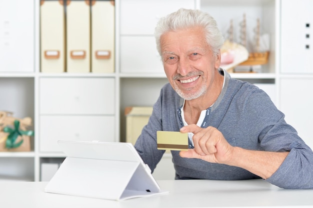 Hombre mayor con tablet y tarjeta de crédito