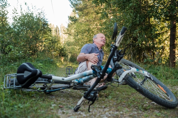 El hombre mayor tiene dolor después de que se cayó de su bicicleta