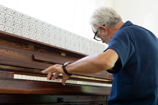 hombre mayor tocando el piano en casa.