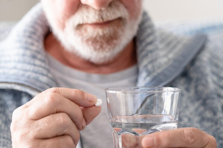 Hombre mayor tomando una pastilla con un vaso de agua concepto de salud y personas