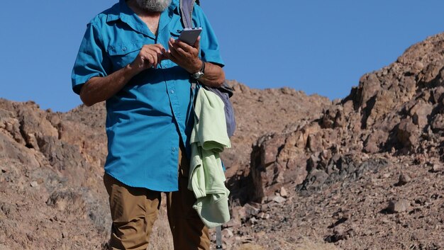 Foto hombre mayor usando teléfono móvil en el desierto