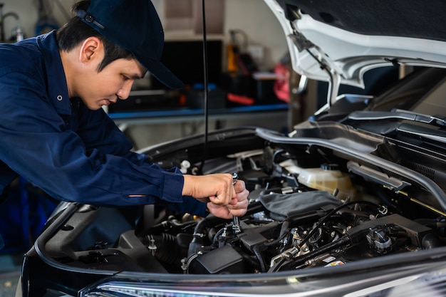 Hombre mecánico con llave para reparar motor, servicio de automóviles