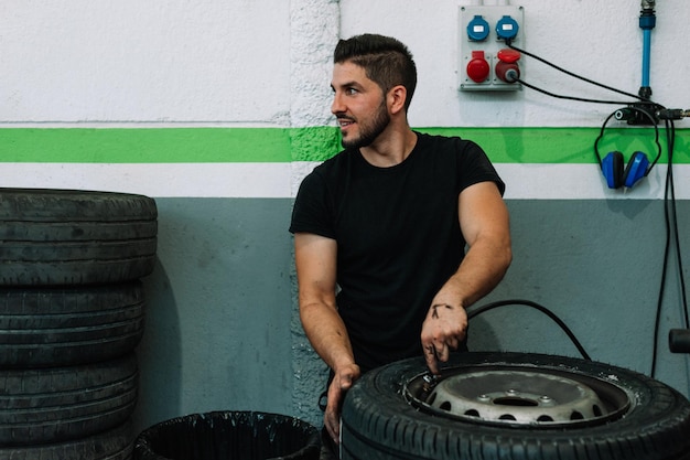 Hombre mecánico que trabaja en el coche en el taller de reparación