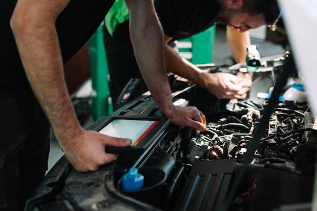 Hombre mecánico que trabaja en el coche en el taller de reparación