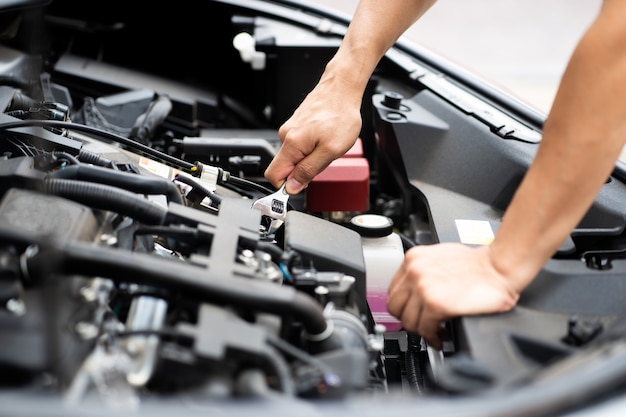 Foto hombre mecánico trabajando y reparando el motor del automóvil en el centro de servicio del automóvil.