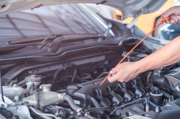 El hombre mecánico verifica el nivel de aceite del motor del motor, la inspección y el autoaprendizaje