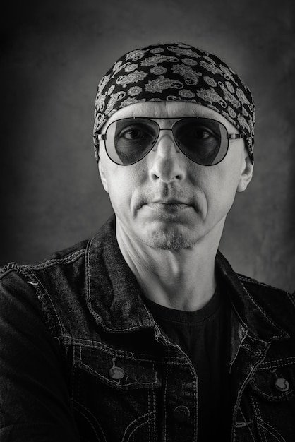 Hombre de mediana edad sin afeitar en camiseta chaleco de mezclilla bandana y gafas de sol Retrato en blanco y negro