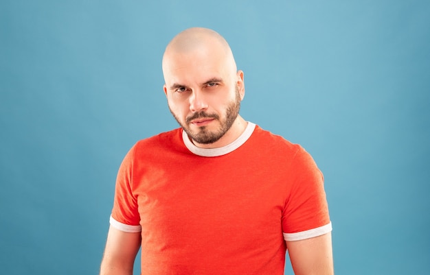 Un hombre de mediana edad con barba y camiseta roja se encuentra con los brazos extendidos y se regocija por la victoria. Aislado.