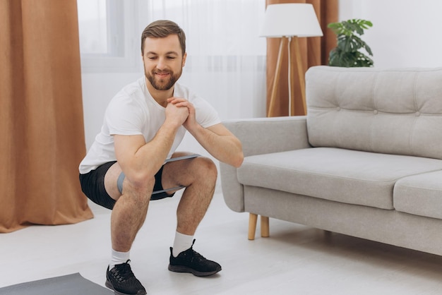 Hombre de mediana edad barbudo atlético positivo que se estira en casa usando una computadora portátil viendo videos deportivos en Internet con clase de fitness en línea espacio de copia Deporte de estilo de vida saludable en autoaislamiento