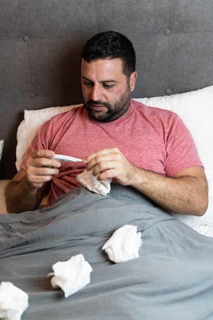 Hombre de mediana edad en cama enfermo con síntomas de gripe.