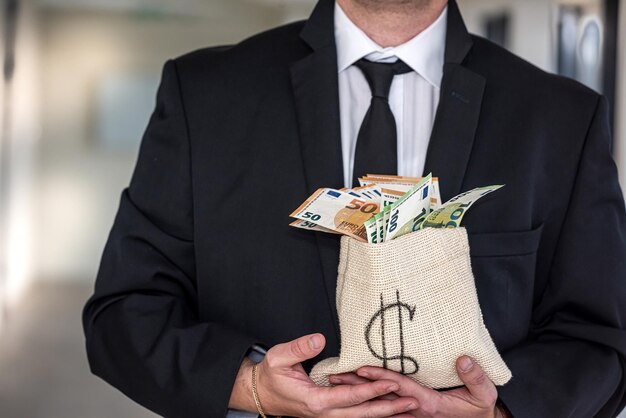 Un hombre de mediana edad con una camisa de negocios sostiene una bolsa de dólares con una cara enojada El concepto de dinero que no quieres dar