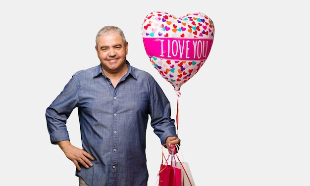 Hombre de mediana edad celebrando el día de San Valentín cruzando los brazos, sonriendo y relajado