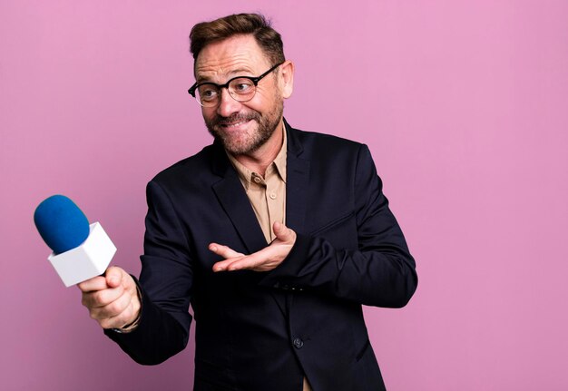 Foto hombre de mediana edad con un concepto de periodista o presentador de micrófono concepto de entrenador deportivo con una pelota de fútbol