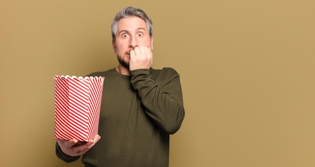 Hombre de mediana edad con un cubo de palomitas de maíz