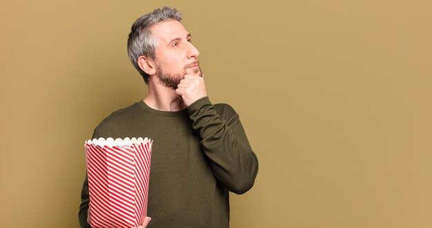 Hombre de mediana edad con un cubo de palomitas de maíz