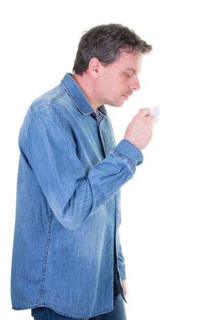 Hombre de mediana edad disfrutando el olor a bebida caliente té o café anticipando el sabor dulce y mirando