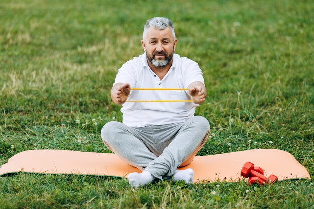 Hombre de mediana edad haciendo ejercicio con cinta al aire libre. deporte