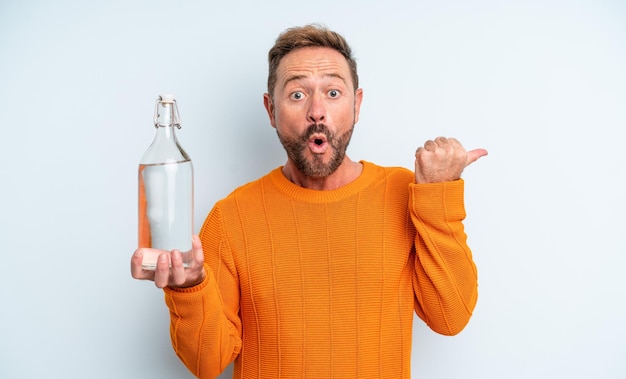 Hombre de mediana edad mirando asombrado con incredulidad. concepto de botella de agua