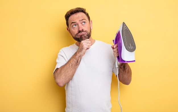 Hombre de mediana edad pensando, sintiéndose dudoso y confundido. concepto de plancha de ropa