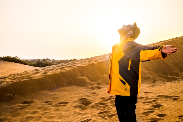 Hombre de mediana edad que disfruta de la libertad y explora la actividad de ocio abriendo los brazos y abrazando la naturaleza. lugar árido del desierto para un estilo de vida alternativo y tiempo de vacaciones. verano y puesta de sol