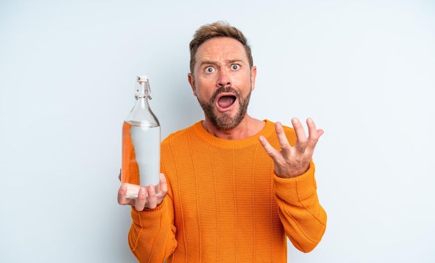 Hombre de mediana edad que parece desesperado, frustrado y estresado. concepto de botella de agua