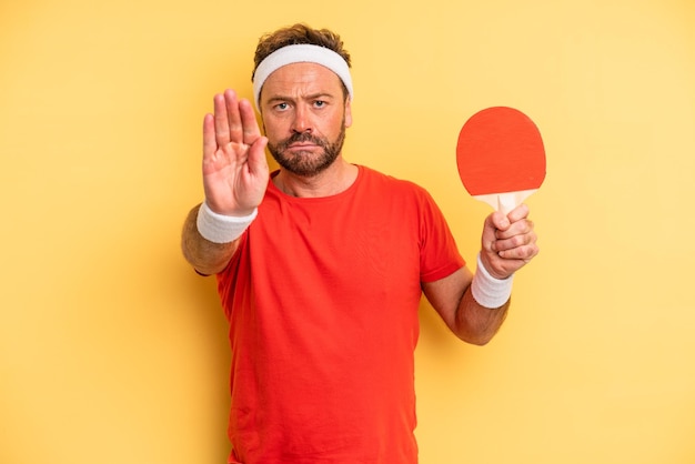 hombre de mediana edad que parece serio mostrando la palma abierta haciendo un gesto de parada. concepto de ping pong