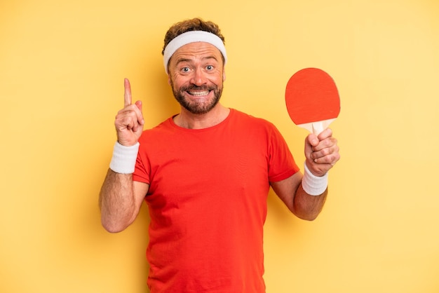 Hombre de mediana edad que se siente como un genio feliz y emocionado después de darse cuenta de una idea del concepto de ping pong