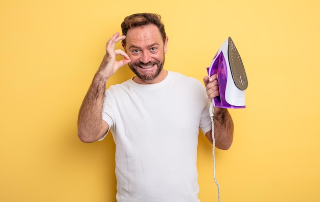 Hombre de mediana edad que se siente feliz mostrando aprobación con gesto bien concepto de hierro de ropa