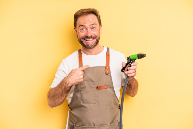 Hombre de mediana edad que se siente feliz y se señala a sí mismo con entusiasmo. concepto de manguera de jardinero