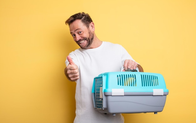 Hombre de mediana edad que se siente orgulloso, sonriendo positivamente con los pulgares hacia arriba. concepto de portador de mascotas