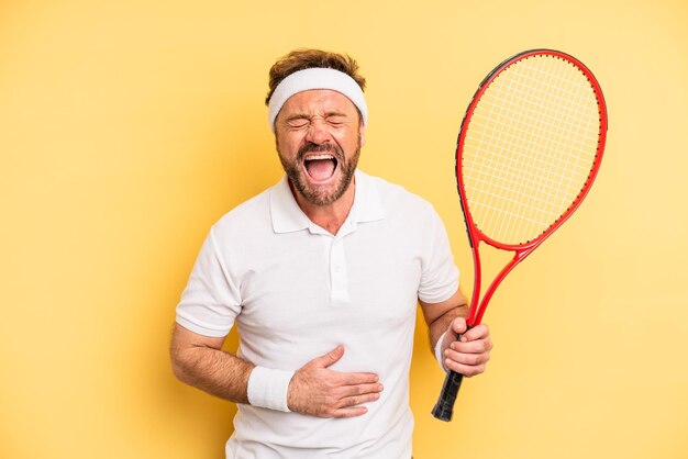 Hombre de mediana edad riéndose a carcajadas de alguna broma hilarante. concepto de tenis