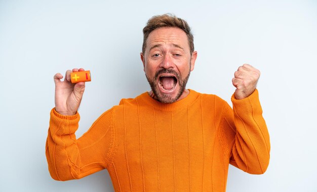 Hombre de mediana edad sintiéndose conmocionado, riendo y celebrando el éxito. concepto de batería