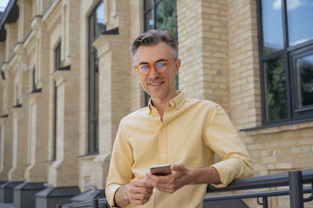 Hombre de mediana edad con smartphone, internet, de pie en la calle