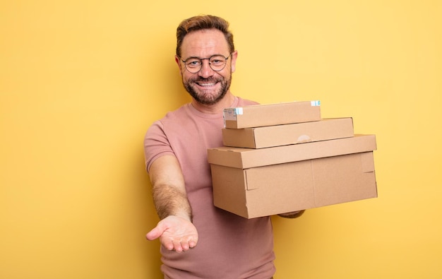 hombre de mediana edad sonriendo alegremente con amabilidad y ofreciendo y mostrando un concepto. concepto de cajas de paquetes