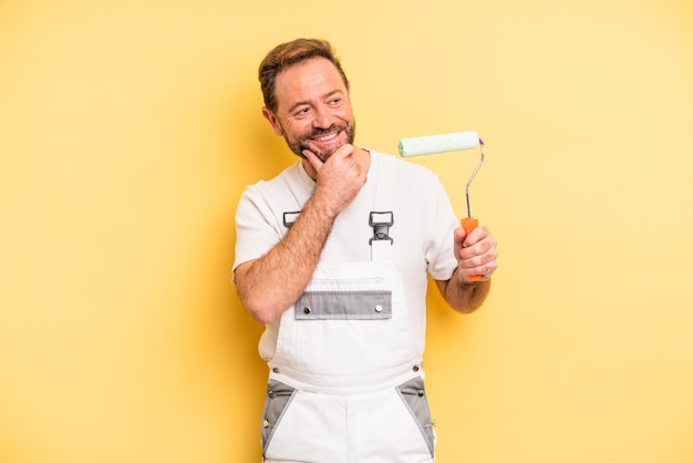 Foto hombre de mediana edad sonriendo con una expresión feliz y segura con la mano en la barbilla. concepto de hogar de pintura