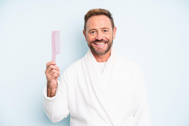 Hombre de mediana edad sonriendo felizmente con una mano en la cadera y confiado. concepto de peine de pelo