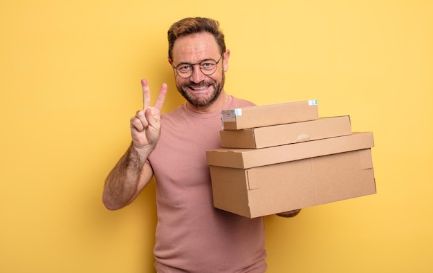 Hombre de mediana edad sonriendo y luciendo amigable mostrando el concepto de cajas de paquetes número dos