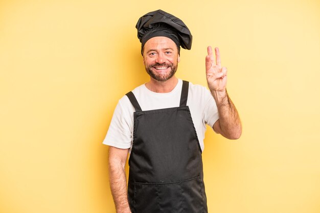 Hombre de mediana edad sonriendo y luciendo amigable, mostrando el número tres. concepto de cocinero