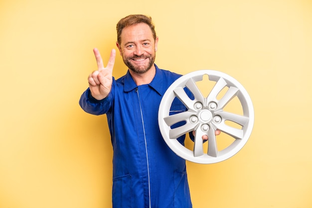 Hombre de mediana edad sonriendo y luciendo feliz, gestando victoria o paz. concepto de mecánico de automóviles