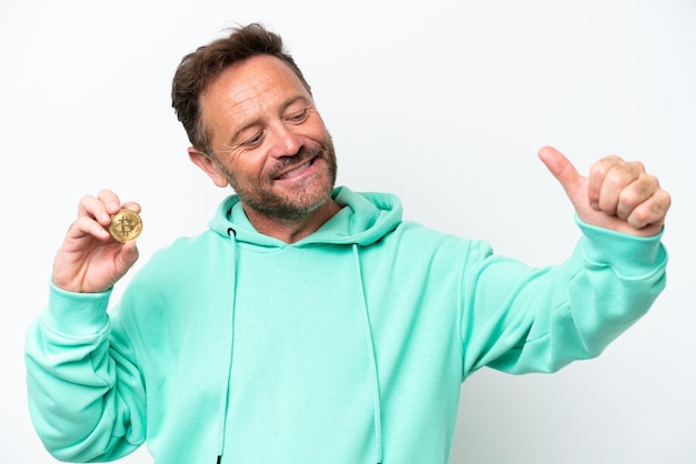 Foto hombre de mediana edad sosteniendo un bitcoin sobre un fondo aislado dando un gesto de pulgar hacia arriba