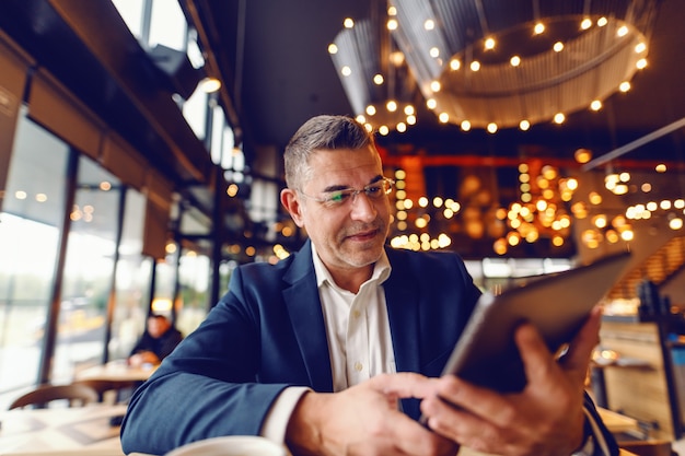 Hombre de mediana edad con tableta en café.