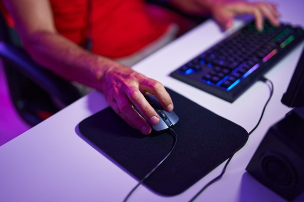 Hombre de mediana edad usando teclado y mouse de computadora en la sala de juegos