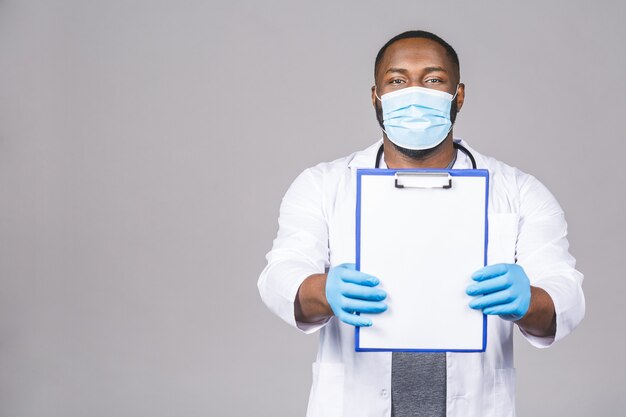 Hombre médico afroamericano en guantes de mascarilla. Sosteniendo el portapapeles.